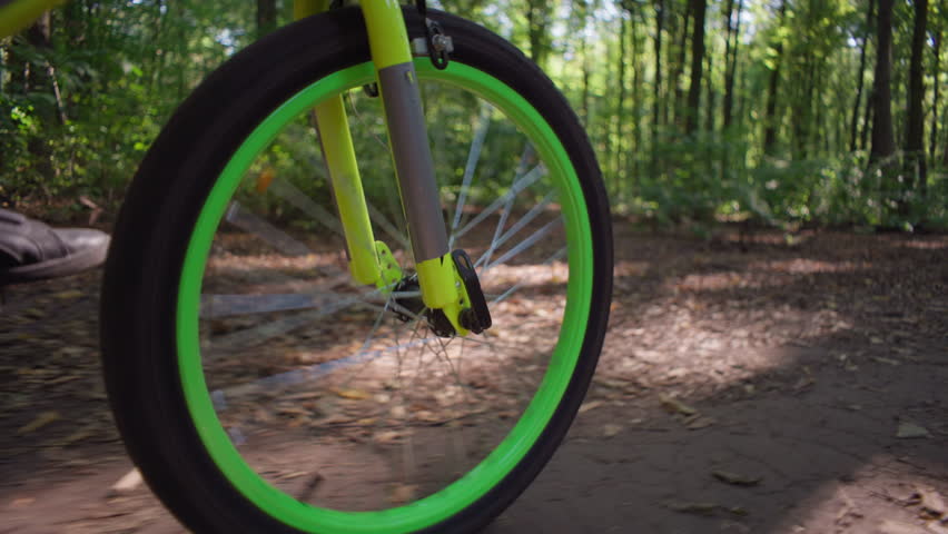A close-up of the wheel of a children's bicycle riding in the park. Active recreation cycling in the forest. High quality 4k footage