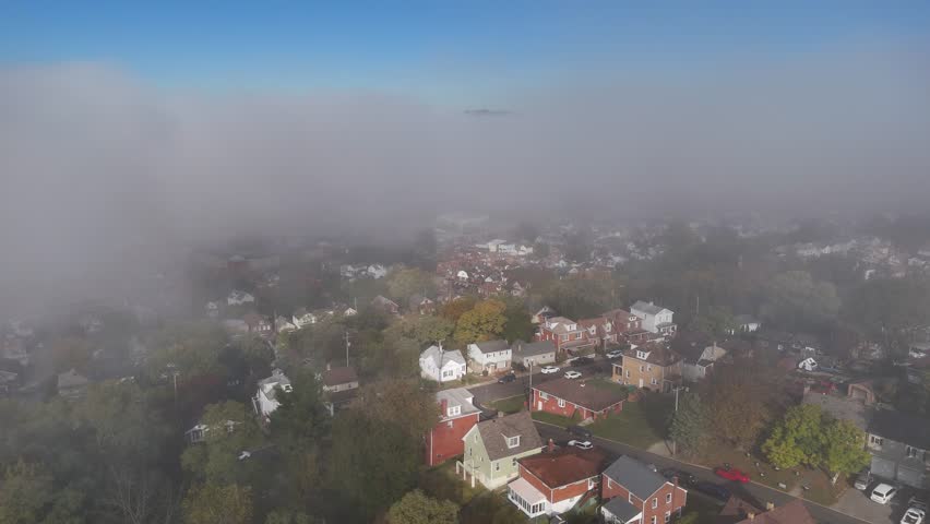 A foggy aerial view above a small New England style town and neighborhood on an Autumn morning. Pittsburgh suburb.	