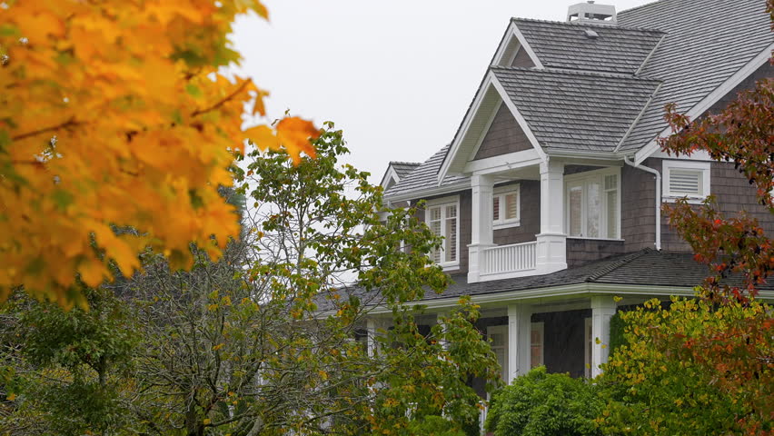 Establishing shot. Two story stucco luxury house with big tree and nice landscape at fall rainfall in Vancouver, Canada, North America. Day time on October 2024. ProRes 422 HQ.