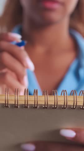 Fingers gently turn the pages of a spiral notebook filled with ideas, evoking creativity and the joy of writing. Relaxing moments of inspiration captured in a cozy home setting.