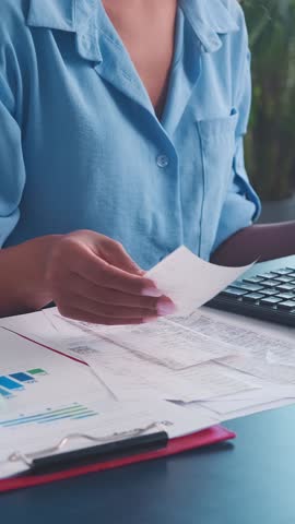 In a cozy workspace, someone meticulously sorts through receipts while calculating expenses with a calculator. The warm sunlight adds a serene touch to the focused atmosphere.