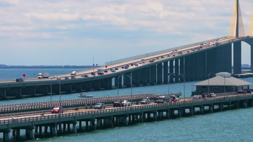Sunshine Skyway Bridge over Tampa Bay in St Petersburg in Florida with fishing pier and driving traffic cars. Transportation infrastructure in USA