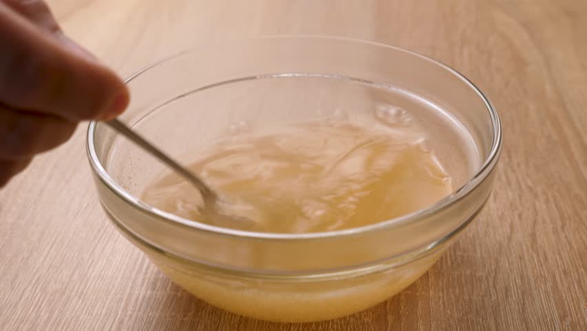 Hot water is poured into a bowl, in which yellow jelly is dissolved. Preparation of gelatin desserts.