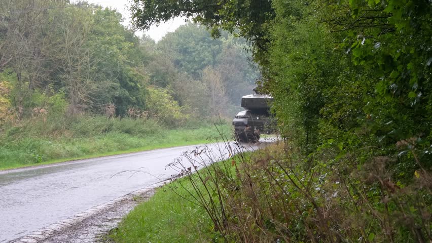 close-up of commander and gunner atop a British army Challenger 2 II FV4034 main battle tank as it drives close by.