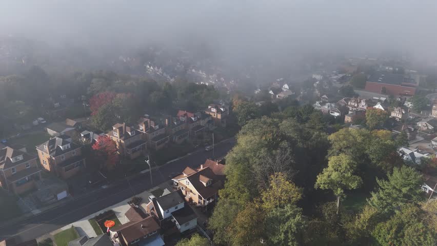 A foggy forward aerial view above a small New England style town and neighborhood on an Autumn morning. Pittsburgh suburbs.  	