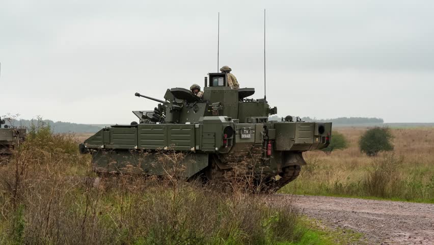 British army 245 Ajax AFV, ISTAR tank tracked combat vehicle driving around a second stationery Ajax.