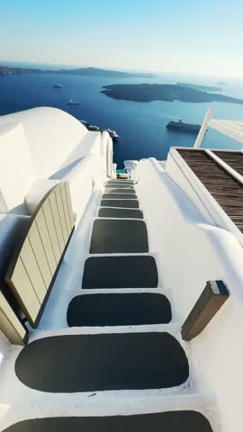 White architecture in Santorini island, Greece. Walking down the steps to the sea. Blue sea and the blue sky at sunset. Travel and summer vacation concept. Vertical video
