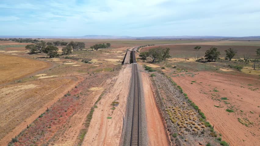 A drone view of the Ghan railway line in a vast rural area with blue sky in Coober Pedy town, Australia