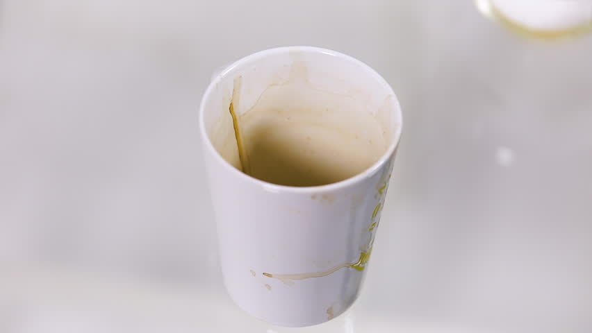 In a glass with dirty stains from coffee or tea, pour a spoonful of sugar. Close up.