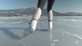 SLOW MOTION, LOW ANGLE, CLOSE UP: Sporty woman in grey and white leggings ice skates across the frozen lake and towards the snowcapped mountain in the distance. Female tourist ice skating in nature - Powered by Shutterstock - Get 15% off with code: PIKWIZARD15