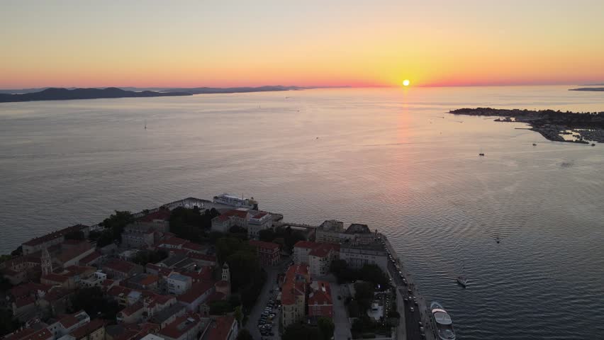 A drone scenic view over the coastal Zadar city with a calm seafront at sunset in Croatia