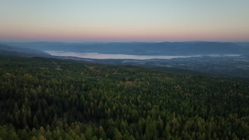 An aerial view of Myra Canyon Trestles during Sunrise with a lake in the background, in Kelowna, Myra-Bellevue Park, British Columbia, Canada
