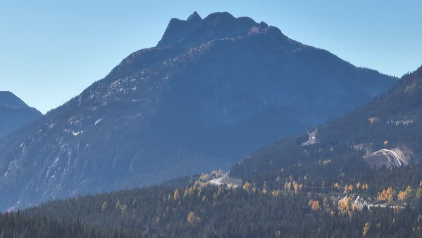 A drone view of mountains landscape covered by fall foliage, against blue sky at Myra Canyon Park in Kelowna, British Columbia, Canada