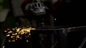 A worker uses a handheld grinder on metal, with sparks flying. Protective gloves highlight safety in this industrial metalworking environment. - Powered by Shutterstock - Get 15% off with code: PIKWIZARD15