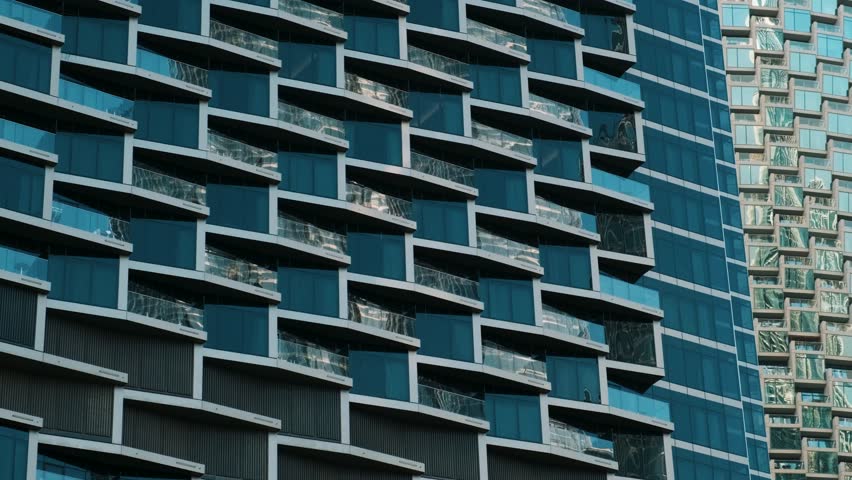 Close-up of contemporary glass building facades with reflections, showcasing modern urban architecture and geometric design in Dubai city, UAE. Abstract architecture background