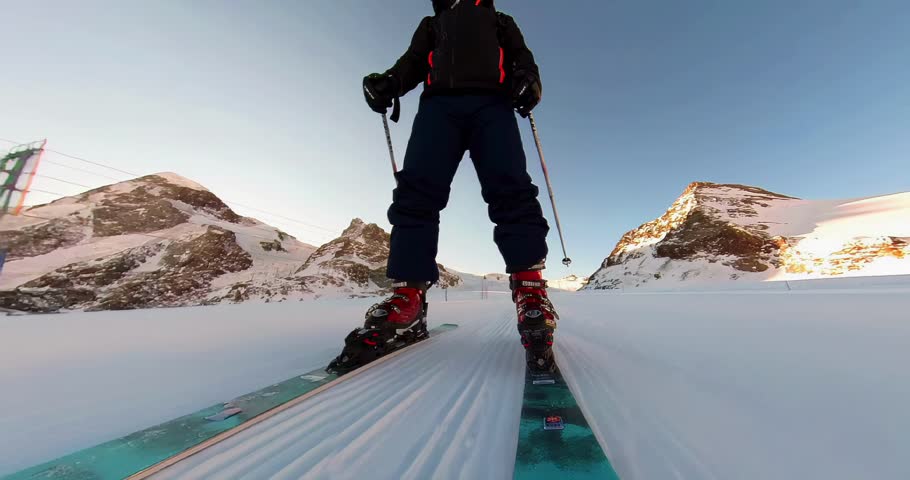 A low angle footage of a man skiing on a sunny day, with the mountain landscape in the background in Zermatt, Switzerland