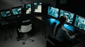 Full high-angle shot of two multiethnic security officers working in control room, Caucasian female guard noticing suspicious activity on CCTV cameras, discussing with African American male colleague - Powered by Shutterstock - Get 15% off with code: PIKWIZARD15