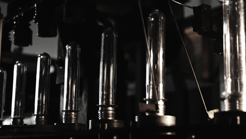 Line for the production of plastic bottles from blanks using the inflation method. Line for pet containers. The raw shape of a plastic water bottle on a conveyor belt.