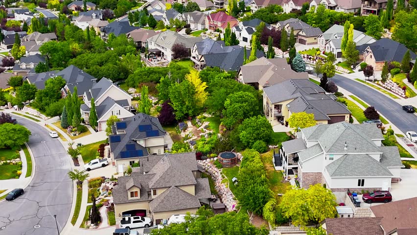 A drone view showing the cityscape of North Salt Lake, luxurious houses with greenery and paved roads in Utah on a sunny day