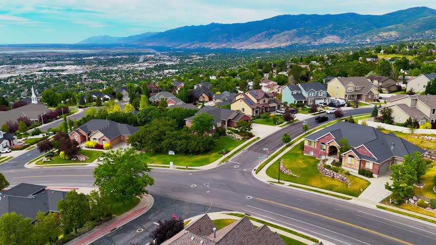 A drone view showing the cityscape of North Salt Lake, luxurious houses with greenery and paved roads in Utah on a sunny day