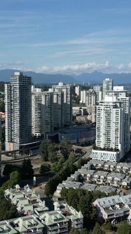 Modern Cityscape With Residential Towers, Waterfront Views, And Mountains Under Blue Sky. New Westminster, BC, Canada.