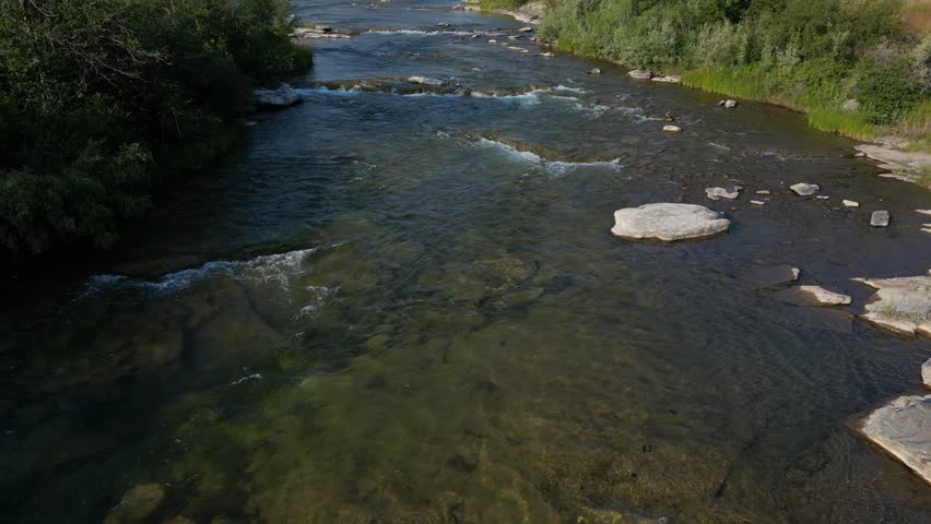 Drone footage moving towards a waterfall with clear water flowing over rocks. Interior British Columbia, Canada.