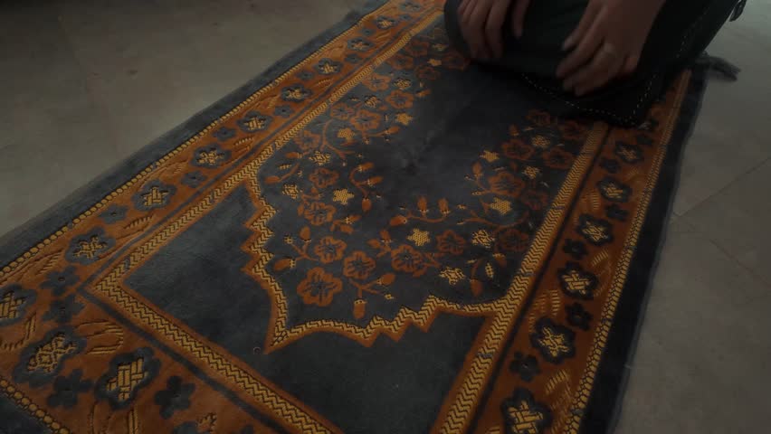 A close-up video of a muslim women folding a prayer mat after offering namaz. An intricate details and serene atmosphere of the moment.