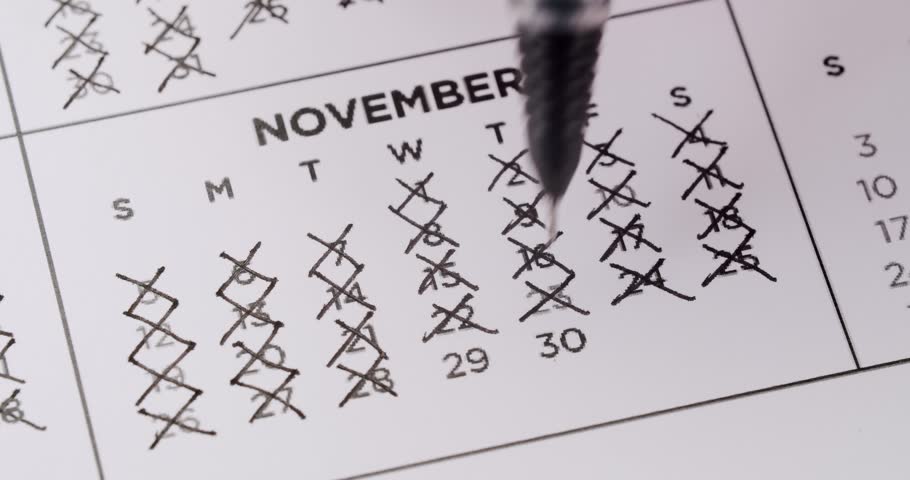 Close-up of a November calendar with crossed-out dates and a pen marking a specific day, representing time management, planning, and schedules.