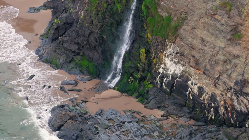 An aerial footage of the Tresaith Waterfall pouring into St George's Channel in daytime in Tresaith village in Ceredigion, Wales, UK
