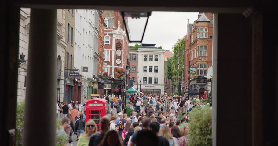 London, UK - 10.08.2024: A lively view of Covent Garden in London, with a bustling crowd and iconic red telephone booth.