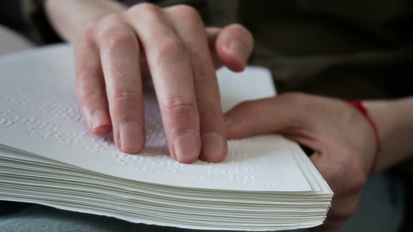 Close-up shot of hand of unrecognisable man reading page of book written with tactile system
