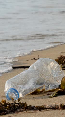 Empty plastic bottles on sand beach. Pollution and environmental problem. Green planet concept