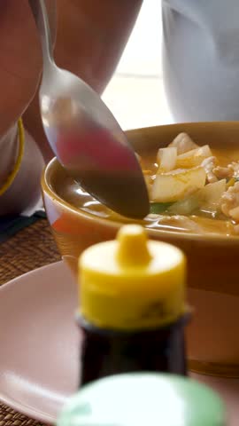 Hot and sour Thai soup cooked with shrimp or prawns, Tom Yum soup. Delicious homemade dish in brown bowl with spoon. Ingredients and vegetables. Fragrant spices and herbs used in seafood broth