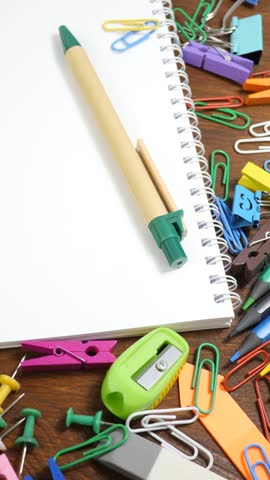Various tools used in an office. School stationery on brown wooden table: coloured pencils, paper clips, shavings, smiling binder clips. Education or knowledge