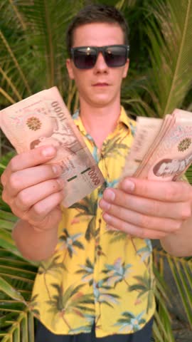 Caucasian man counting Thai Baht on the beach in Thailand