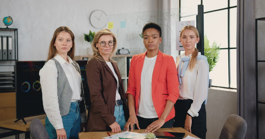 Portrait of business women smiling looking at camera are standing with crossed arms, posing in modern office
