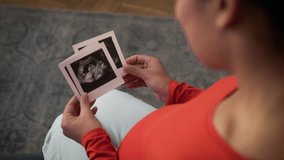Back view unrecognizable African American woman mother mom pregnant girl female enjoying pregnancy anticipation child baby holding looking ultrasound embryo pictures usd photos medicine health at home - Powered by Shutterstock - Get 15% off with code: PIKWIZARD15