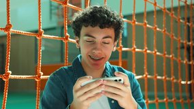 Caucasian male boy teen Hispanic guy pupil Latina man teenager playing internet video game online gaming mobile phone excited smartphone play break at school university college gadget addict gamer - Powered by Shutterstock - Get 15% off with code: PIKWIZARD15