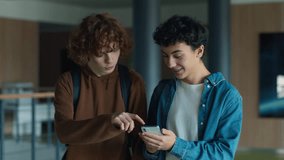 Two teenagers friends Caucasian males men guys pupils students schoolboys walking going in corridor university college school boys looking in mobile phone app shocked laugh smile talking online news - Powered by Shutterstock - Get 15% off with code: PIKWIZARD15