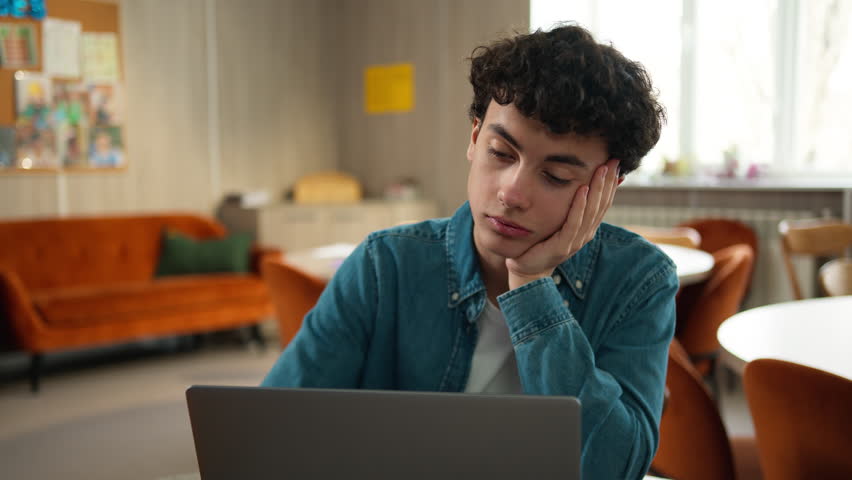 Tired stressed headache overworked sad upset Caucasian male student guy pupil boy teen teenager studying laptop learning online education internet homework prepare to exams school college university