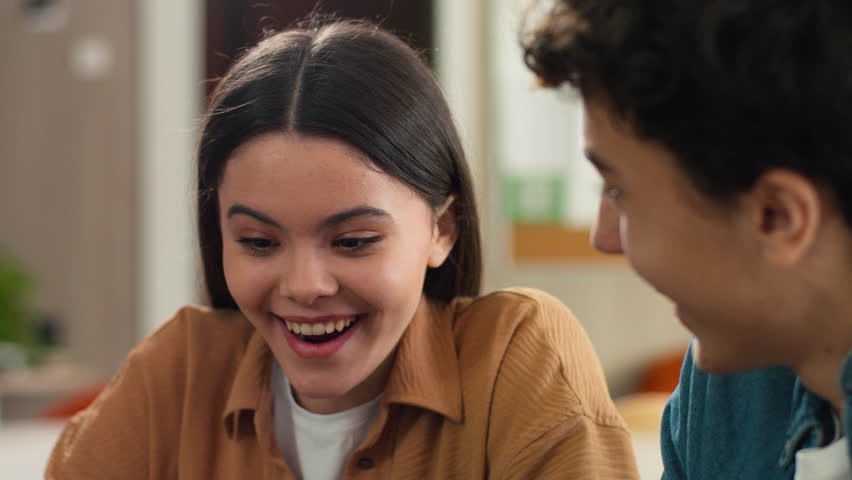 Two Caucasian students pupils friends man woman girl guy boy female male studying together learning homework school project study smiling talking cooperation teamwork education university college