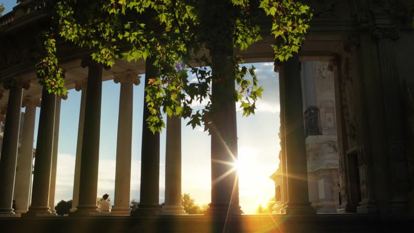 Retiro park at sunset, park Retiro in Madrid, capital of Spain, Alfonso monument, evening sun through columns of the monument, walk in Retiro park at sunset