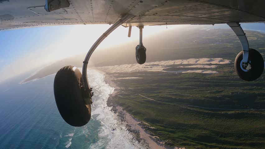 Light three wheels training airplane doing steep turns to the left and right following coastline near the ocean. Training flight. View from bottom of aircraft.