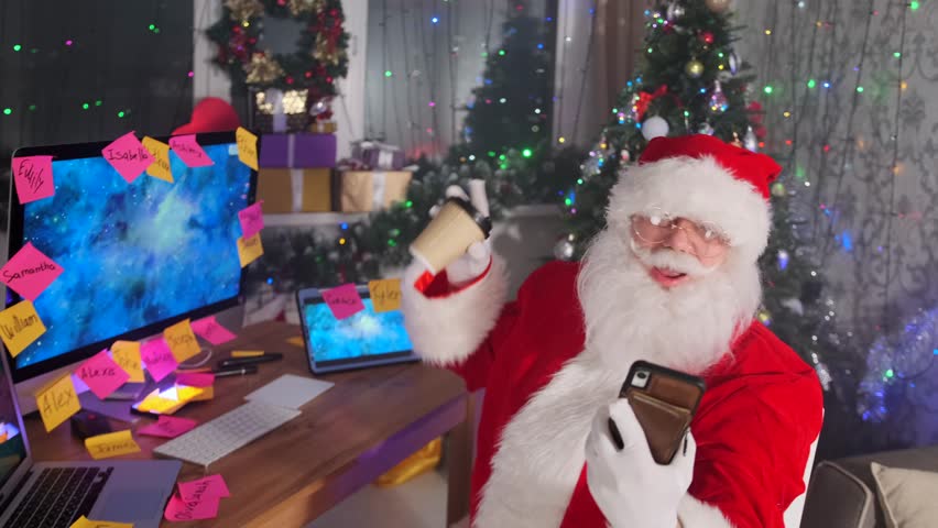 Santa smiles on the phone, taking a coffee break. In the background, Christmas gifts and a decorated tree enhance the cozy, festive atmosphere