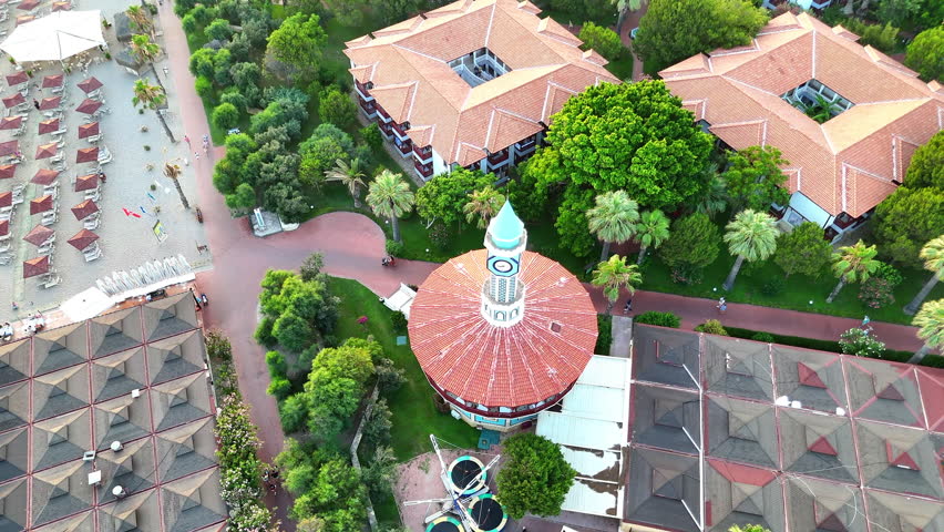 Sunset Over Turkish Clock Tower with Scenic Mountains and Villa Roofs from Drone