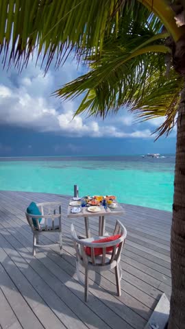 Breakfast by the turquoise ocean of the Maldives, under a palm tree, with a table set with delectable treats. 🏝️ 
