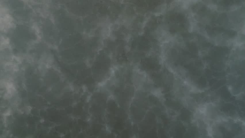 Drone captures dense fog rolling through forested area, tendrils of mist obscuring water at dusk, natural texture background with space for text