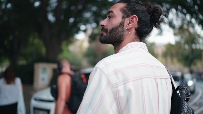 Tourist smiling as he enjoys walk through streets of Barcelona, looking up at city