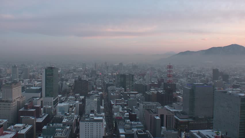 SAPPORO, HOKKAIDO, JAPAN : Aerial high angle sunset view of cityscape of Sapporo city. View of buildings and street traffic around Susukino area. Time lapse shot, dusk to night in winter.