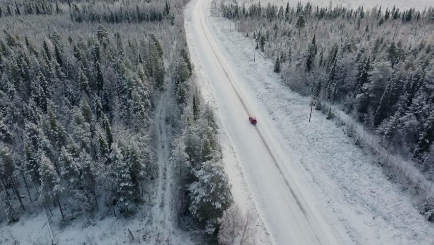 Red Car Driving on Snow Covered Road in Vast Open Arctic Winter Landscape in Northern Sweden, Travel to the Arctic Circle